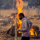 A man walks past burning funeral pyres of people, who died due to the coronavirus disease (COVID-19), at a crematorium ground in New Delhi